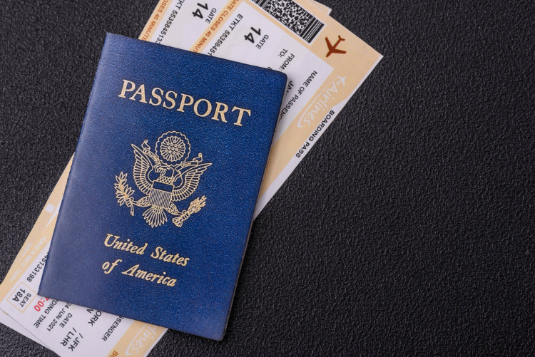 United states of america passport, airline tickets and money on a dark concrete background.